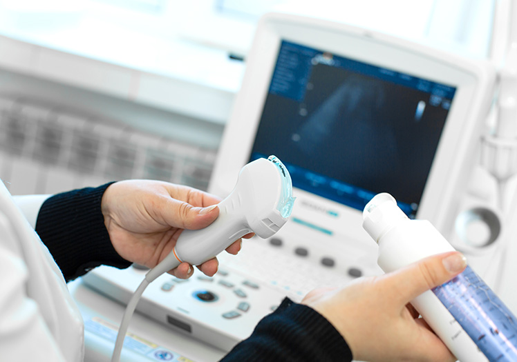 An individual operating a medical ultrasound machine, with a monitor displaying an image of a fetus.