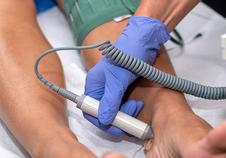 An image showing a medical professional using an electronic monitoring device on a patient s leg.